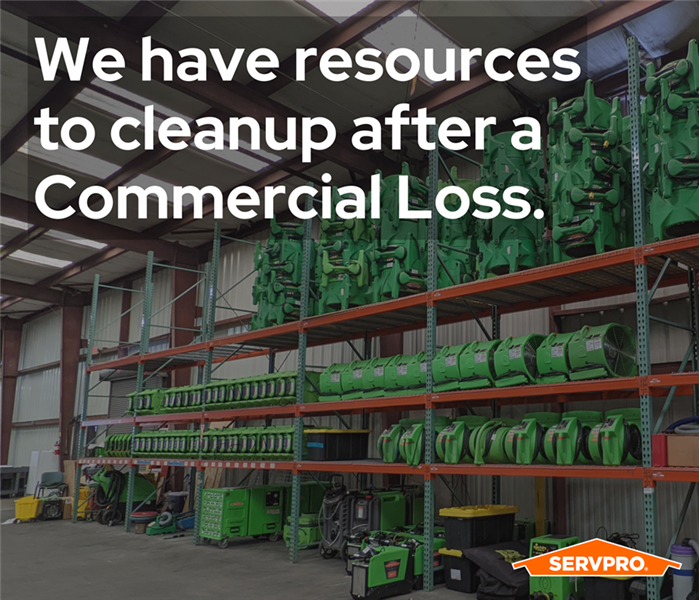 a storage rack full of air movers along a wall, going up the side of an industrial warehouse, SERVPRO green